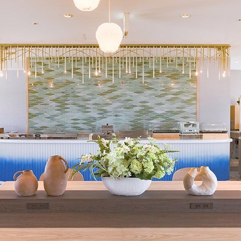 Ein eleganter Restaurantbereich mit einem großen Tisch, dekoriert mit frischen Blumen und stilvollen Keramiken.