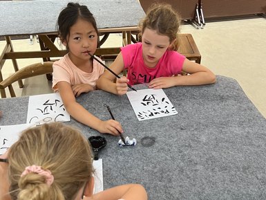 Kinder üben chinesische Kalligrafie auf Papier – China Reise mit Kindern