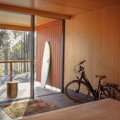 Ein modernes Hotelzimmer mit Holzverkleidung, einem Surfbrett an der Wand und einem Fahrrad in der Ecke.