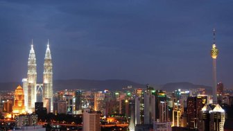 Skyline von Kuala Lumpur erstrahlt bei Nacht mit hell erleuchteten Wolkenkratzern – Malaysia & Borneo Familienreise