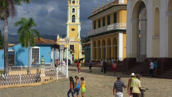 Eine belebte Straße in Trinidad, Kuba, mit bunten Gebäuden und Menschen, die fröhlich umhergehen.