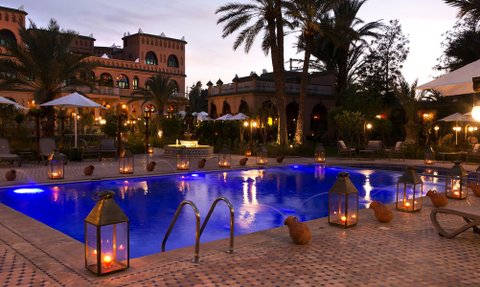 Ein eleganter Pool mit blauem Wasser, umgeben von Palmen und stimmungsvoller Beleuchtung, schafft eine entspannende Atmosphäre.