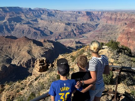 Drei Kinder stehen am Rand des Grand Canyon und bewundern die beeindruckende Aussicht auf die tiefen Schluchten und Felsen.