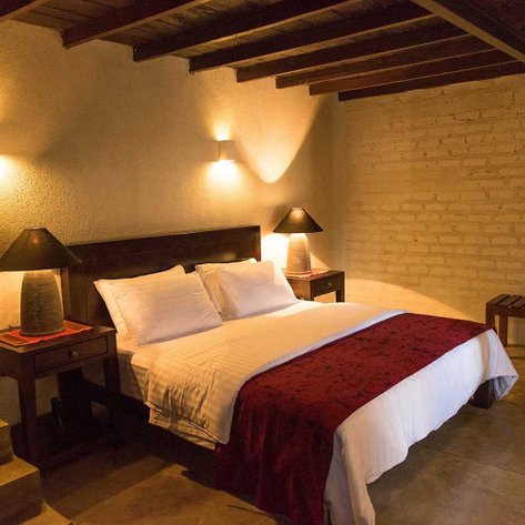 Ein gemütliches Schlafzimmer mit einem großen Bett, das mit weißen und roten Bettwäsche dekoriert ist, und sanfter Beleuchtung.