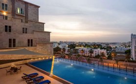 Außenpool mit Ausblick auf Muscat im Radisson Hotel Muscat Panorama bei Sonnenuntergang - Oman Familienreise