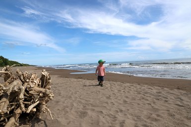 Kind spielt fröhlich am weißen Sandstrand im Tortuguero Nationalpark – Costa Rica Reise mit Kindern