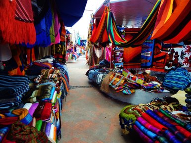 Bunte Textilien und handgefertigte Waren füllen die Stände auf dem Markt, während die Farben lebhaft und einladend wirken.