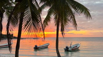 Bunte Abendstimmung am Strand von Akumal mit Palmen und Booten im Wasser – Mexiko Familienreise