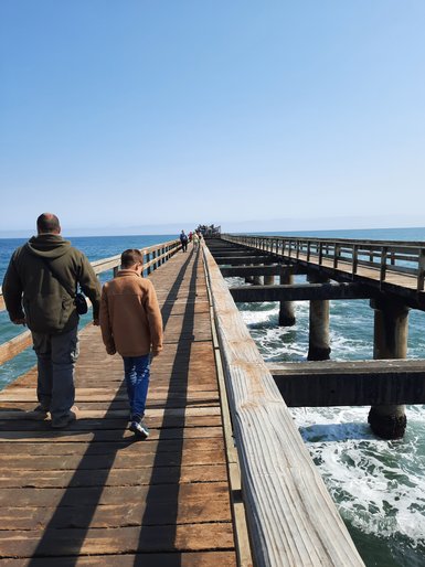 Zwei Menschen laufen einen langen Bootssteg entlang - Namibia mit Jugendlichen