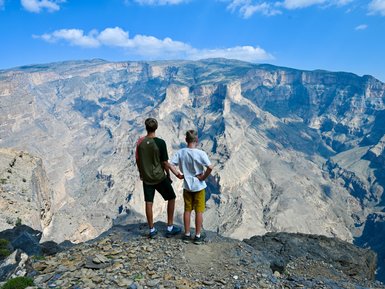 Zwei Kinder genießen die Aussicht vom Jebel Shams auf die spektakuläre Berglandschaft – Oman mit Kindern