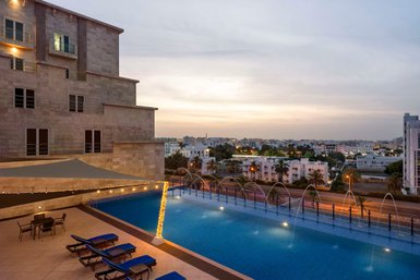 Außenpool mit Ausblick auf Muscat im Radisson Hotel Muscat Panorama bei Sonnenuntergang - Oman Familienreise