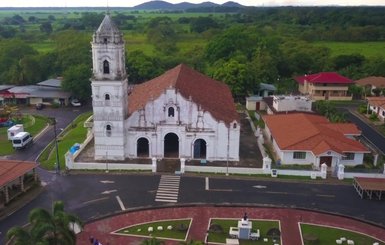 Die majestätische Kirche mit rotem Ziegeldach steht umgeben von üppigem Grün und einem kleinen Spielplatz im Vordergrund.