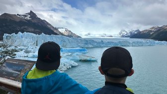 Zwei Kinder stehen am Ufer und blicken auf den beeindruckenden Perito-Moreno-Gletscher im Nationalpark Los Glaciares.