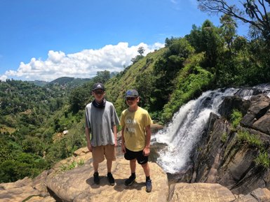 Zwei Kinder stehen vor einem Wasserfall in der bergigen Umgebung von Ella – Sri Lanka Reise mit Kindern