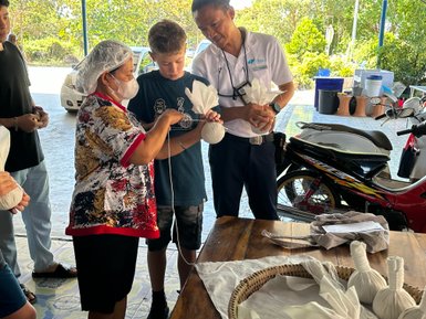 Kräutersverpacken von einheimischer Frau und Kind – Thailand Familienreise