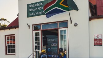 Zwei Kinder stehen vor dem Walvis-Haus in Hermanus, das mit einer südafrikanischen Flagge geschmückt ist.