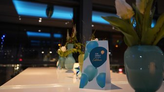 Ein eleganter Tisch mit einer festlichen Karte und frischen Blumen in blauen Vasen, die eine feierliche Atmosphäre schaffen.