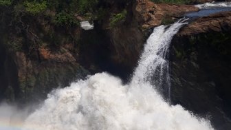 Ein beeindruckender Wasserfall stürzt mit kraftvollem Wasser in eine Schlucht, umgeben von üppigem Grün und strahlend blauem Himmel.