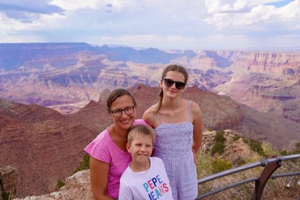 Eine Familie posiert am Grand Canyon, umgeben von beeindruckenden Felsformationen und einer weiten Landschaft.