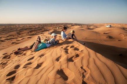 Kinder sitzen gemeinsam auf einer Wüstendüne – Oman Familienreise