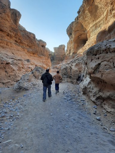 Ein Kind und ein Guide laufen gemeinsam durch einen Canyon - Namibia Rundreise mit Kindern