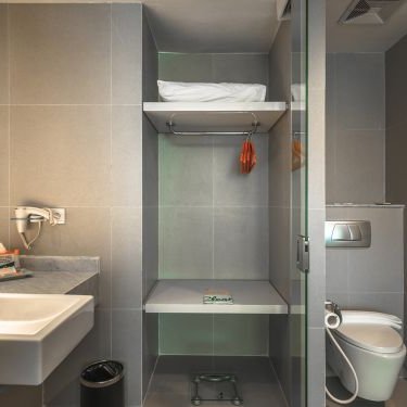 Das moderne Badezimmer zeigt eine elegante Dusche, ein Waschbecken und eine Toilette in neutralen Grautönen.