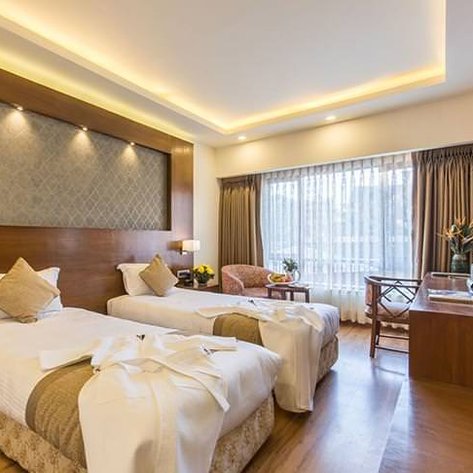Ein elegantes Hotelzimmer mit zwei Einzelbetten, warmem Holzdekor und sanfter Beleuchtung, ideal für Familienaufenthalte.