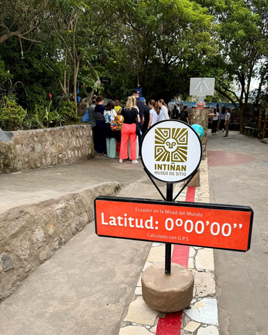 Eine Gruppe von Menschen versammelt sich um einen Stand im Intiñan-Museum, umgeben von üppiger Vegetation und Natur.