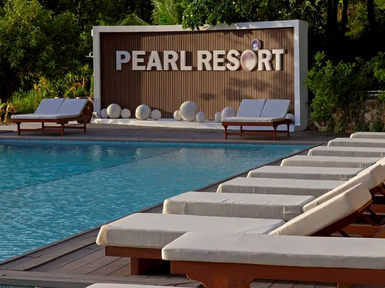 Ein einladender Poolbereich im Pearl Resort, umgeben von Liegen und einer stilvollen Wand mit dem Resort-Namen.