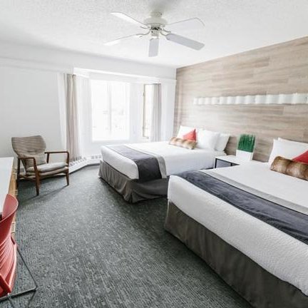 Ein modernes Hotelzimmer mit zwei Betten, einem Fernseher und einem gemütlichen Sessel, ideal für entspannte Aufenthalte.