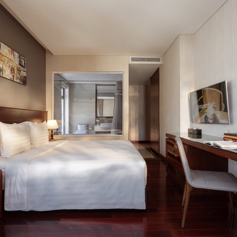 Ein elegantes Hotelzimmer mit einem großen Bett, einem Schreibtisch und einem Fernseher an der Wand, das modern eingerichtet ist.