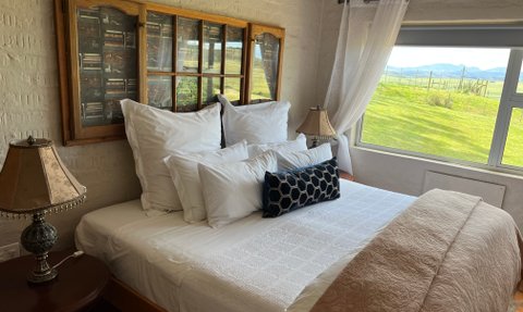 Ein gemütliches Schlafzimmer mit einem großen Bett, umgeben von weißen Kissen und einer eleganten Lampe auf dem Nachttisch.