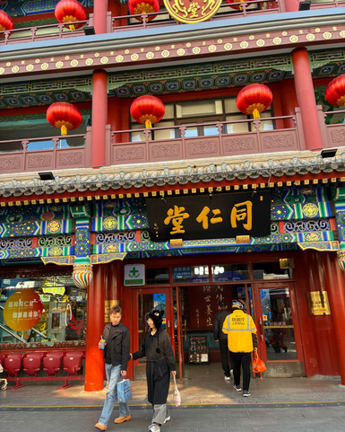 Ein Paar schlendert durch eine belebte Straße, umgeben von bunten Laternen und traditioneller Architektur in Peking.