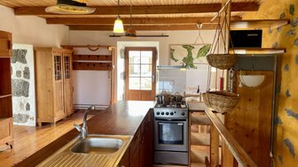 Eine helle, einladende Küche mit Holzregalen, einem großen Tisch und einem Herd, der bereit ist für das Kochen.