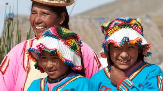 Eine fröhliche Uros-Familie posiert in traditioneller Kleidung auf den schwimmenden Inseln des Titicacasees.