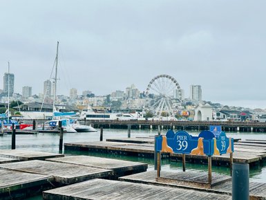 Der Pier 39 in San Francisco zeigt eine lebhafte Hafenlandschaft mit Booten und einem Riesenrad im Hintergrund.