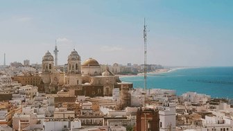 Ein atemberaubender Blick auf die Stadt Cádiz mit weißen Gebäuden und der goldenen Kuppel einer Kirche im Hintergrund.