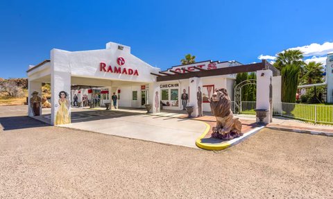 Die Außenansicht des Ramada-Hotels zeigt eine helle Fassade mit einem großen Eingang und einem Löwenstatuen im Vordergrund.