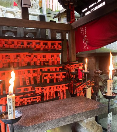 Ein Altar mit brennenden Kerzen und leuchtend orangefarbenen Torii, die für Glück und Wohlstand stehen.