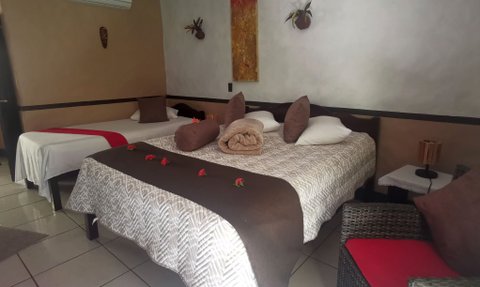 Ein gemütliches Zimmer mit zwei Betten, dekoriert mit Kissen und Blumen, strahlt eine entspannte Atmosphäre aus.