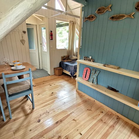 Ein gemütlicher Raum mit einem Holztisch, gedeckt mit Geschirr und Gläsern, strahlt eine einladende Atmosphäre aus.