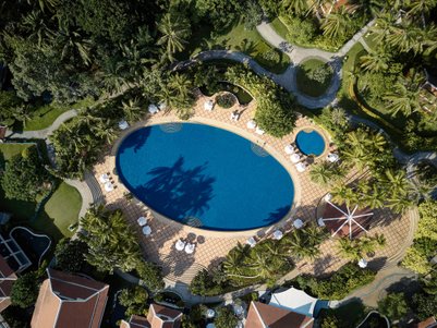 Ein weitläufiger Pool umgeben von üppigem Grün und Palmen, ideal für Entspannung und Erholung in tropischer Umgebung.