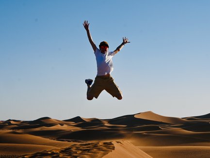 Kind voller Freude beim Springen auf den weichen Sanddünen der Sahara – Marokko mit Kindern