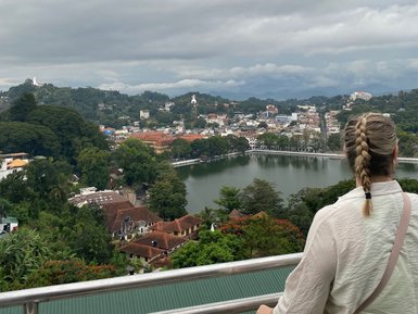 Teenagerin steht auf einem Aussichtspunkt und blickt über die Stadt Kandy – Sri Lanka Reise mit Kindern