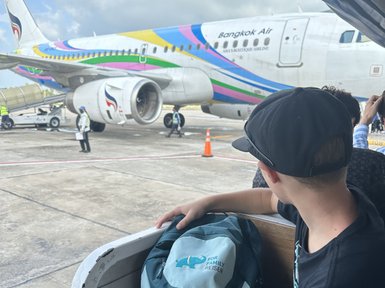 Kind mit Rucksack wartet auf Boarding ins Flugzeug - Thailand mit Kindern