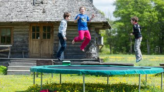 Drei Kinder springen fröhlich auf einem Trampolin herum