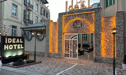 Der Eingangsbereich des Ideal Hotels zeigt eine kunstvoll gestaltete Fassade mit warmem Licht und einem eleganten Tor.