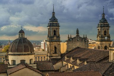 Die beeindruckenden Türme der Kathedrale von Bogotá ragen majestätisch über die Dächer der Stadt, umgeben von dramatischen Wolken.