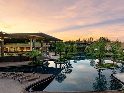 Ein eleganter Außenbereich eines Resorts mit einem glitzernden Pool, umgeben von üppigem Grün und einem malerischen Sonnenuntergang.