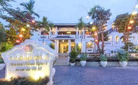 Das Ancient House Resort in Hoi An zeigt eine elegante Fassade mit bunten Laternen und üppiger Vegetation im Vordergrund.
